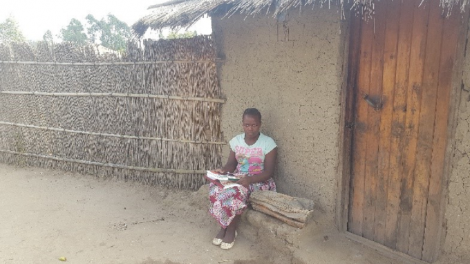 Constância sitting in front of her house and ready to go to school