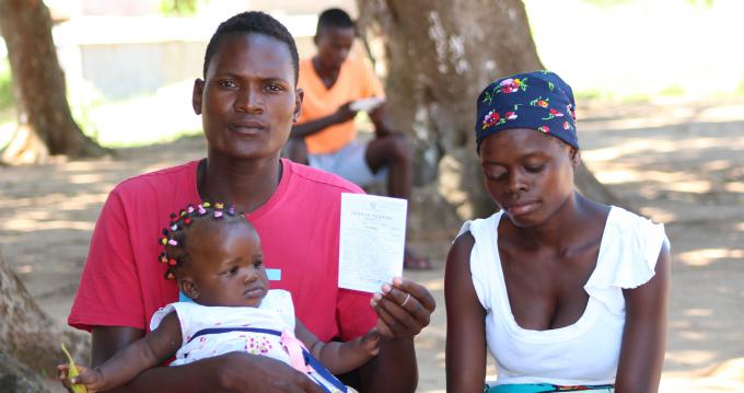 Plínio Rafael Cossa, holding in his hand the ballot of his daughter Luciana, on his lap and next to his wife.